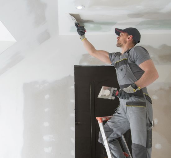 Professional drywall installation and finishing – expert contractor smoothing ceiling joints.